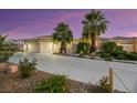 Tan two-story house with two palm trees and a long driveway at dusk at 10275 Tresor Ct, Las Vegas, NV 89135