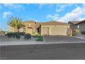 Tan house with tile roof, three-car garage, and lush landscaping at 2080 Twin Falls Dr, Henderson, NV 89044