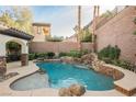 Inviting freeform pool with a rock waterfall feature and a tanning shelf at 2768 Liberation Dr, Henderson, NV 89044