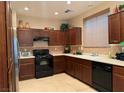 Kitchen with dark brown cabinets, black appliances, and tile floor at 8157 Amy Springs St, Las Vegas, NV 89113