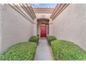 Inviting entryway features a red front door and lush green hedges at 10725 Sky Meadows Ave, Las Vegas, NV 89134