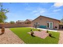 Artificial turf backyard with brick patio, and mature plants at 3028 Gannon Ridge Ave, North Las Vegas, NV 89081