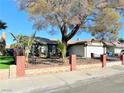 House exterior with brick wall, landscaping, and a large tree in the front yard at 6402 Agua Dr, Las Vegas, NV 89103