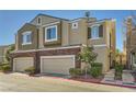 Tan two-story townhome with two-car garage and landscaped front yard at 939 Paisley St, Las Vegas, NV 89145