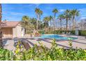 Beautiful community pool and seating area with palm trees and lush landscaping at 10452 Prairie Schooner Ave, Las Vegas, NV 89129