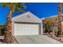 Front view of a house with a white garage door and palm trees at 9612 World Cup Dr, Las Vegas, NV 89117