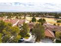 Aerial view of a residential neighborhood with lush greenery, tile roofs, and a golf course in the distance at 7909 Rio Rico Dr, Las Vegas, NV 89113