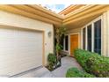 Charming front entrance with a wood door, lovely landscaping, and attached garage at 7909 Rio Rico Dr, Las Vegas, NV 89113