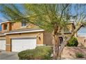 Two-story home with attached garage partially obscured by tree at 3349 Morning Amber St, North Las Vegas, NV 89032