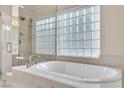 Soaking tub with glass block window and gold fixtures in a bright, modern bathroom at 2617 Huber Heights Dr, Las Vegas, NV 89128