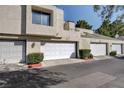 Tan stucco exterior of townhome with white garage doors and landscaping at 8945 Clairton Ct, Las Vegas, NV 89117