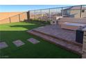 Backyard featuring artificial turf, a paved patio with built in seating, and a privacy fence at 12381 Foxtail Run Ave, Las Vegas, NV 89138