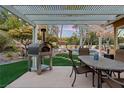 Alfresco dining on patio with pizza oven, artificial turf, and pool view at 2228 Lucerne Ct, Henderson, NV 89014