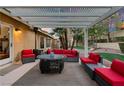 Relaxing patio furniture under pergola with red cushions and fire pit at 2228 Lucerne Ct, Henderson, NV 89014