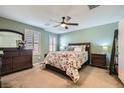 Well-lit bedroom featuring a ceiling fan, wood furniture, and a floral-patterned comforter on the bed at 4650 Ranch House Rd # 42, North Las Vegas, NV 89031