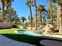 Inviting backyard with a refreshing pool, lush grass, and palm trees at 109 Lakewood Garden Dr, Las Vegas, NV 89148