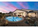 A gorgeous outdoor pool and patio with a fire pit under a colorful evening sky at 2540 E Sparrow Way, Pahrump, NV 89048
