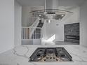 Stylish gas cooktop with modern range hood set in an open-concept kitchen, view to stairs at 5236 Woodlawn Ln, Las Vegas, NV 89130