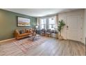 Open living room with wood-look floors, a brown couch, and green accent wall at 9436 Peaceful River Ave # Lot 63, Las Vegas, NV 89178