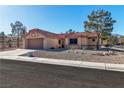 Beige home with desert landscaping, a two-car garage, and a red tile roof at 9037 Grayling Dr, Las Vegas, NV 89134