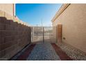 Side entrance with decorative metal gate, gravel, and brick walkway at 6304 Tanzanite Ave, Las Vegas, NV 89130