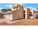 View of two-story home with beige exterior, two-car garage, and desert landscaping at 6712 Painted Canyon Ct, Las Vegas, NV 89130