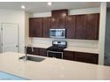 Modern kitchen with dark brown cabinets, stainless steel appliances, and white countertops at 7672 Lush Oasis Ave, Las Vegas, NV 89113