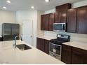 Modern kitchen with dark brown cabinets, stainless steel appliances, and white countertops at 7672 Lush Oasis Ave, Las Vegas, NV 89113