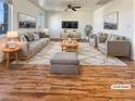 Bright, staged living room featuring hard wood flooring, modern furniture, and two large windows for natural light at 10809 Wrigley Field Ave, Las Vegas, NV 89166