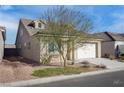 Tan colored house with a two car garage and mature trees at 1348 Mariposa Way, Mesquite, NV 89027