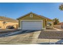 Tan house with a white garage door and driveway at 2210 Cool River Ct, North Las Vegas, NV 89032