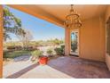 Inviting covered patio with elegant chandelier and views of the beautifully landscaped backyard at 36 Hunt Valley Trl, Henderson, NV 89052