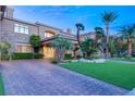 Elegant home with stone accents, lush landscaping, and a brick driveway at 1549 Foothills Village Dr, Henderson, NV 89012