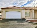 Front view of tan stucco house with tile roof and white garage door at 1900 N Torrey Pines Dr # 132, Las Vegas, NV 89108