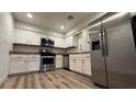 Modern kitchen with stainless steel appliances and wood-look floors at 2136 Chertsey Dr # A, Las Vegas, NV 89108