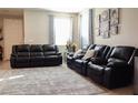 A bright living room with plush black leather sofas, patterned rug, and decorative floral arrangement at 2509 Piacenza Pl, Henderson, NV 89044