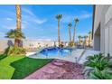 Backyard oasis featuring a sparkling pool with a waterfall, tropical landscaping, and a built-in grill at 278 Iron Duke Ave, Las Vegas, NV 89183