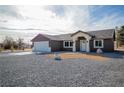 Single story home with a two-car garage, gravel front yard, and covered entrance at 3880 Leonard St, Pahrump, NV 89060