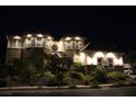 Stone house exterior at night with landscape lighting and lush landscaping at 768 Tozzetti Ln, Henderson, NV 89012