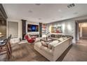 Cozy living room with a fireplace, a large sectional sofa, a red armchair, and a TV mounted above the fireplace at 1705 Corta Bella Dr, Las Vegas, NV 89134