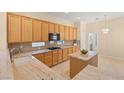 L-shaped kitchen with wood cabinets, granite countertops, and an island at 2000 Poppywood Ave, Henderson, NV 89012