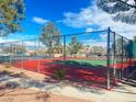 Outdoor community tennis court with well maintained red and green surface and tall fence at 8070 W Russell Rd # 2068, Las Vegas, NV 89113