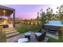 Relaxing backyard featuring a spa, seating, manicured lawn, and privacy hedges at 11015 Sanctuary Cove Ct, Las Vegas, NV 89135