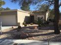 Tan colored house with a two-car garage and nicely landscaped yard at 10321 Junction Hill Dr, Las Vegas, NV 89134