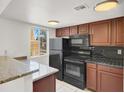 Cozy kitchen featuring black appliances, dark wood cabinets, granite countertops, and a window for natural lighting at 5493 Indian River Dr # 383, Las Vegas, NV 89103
