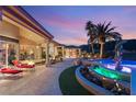 Elegant patio with a fire pit, sun loungers, poolside dolphin fountain, and picturesque palm trees at sunset at 942 Villa Grande Way, Boulder City, NV 89005