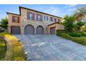 Elegant home with a three-car garage and beautiful stone and stucco exterior, complimented with manicured shrubs at 10117 Summit Canyon Dr, Las Vegas, NV 89144