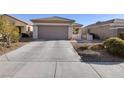 Long concrete driveway leading to a two-car garage surrounded by desert landscaping at 3025 Seaford Peak Dr, Henderson, NV 89052