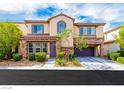 Charming two-story home featuring a stone facade, manicured landscaping, a purple front door, and an attached two-car garage at 8396 Waylon Ave, Las Vegas, NV 89178