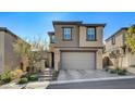 Stylish home with a neutral color palette, a two-car garage and charming landscaping under a clear blue sky at 889 Ariel Heights Ave, Las Vegas, NV 89138